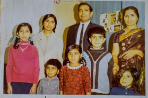 Anju on the left, wearing a red jumper with her father, mother and siblings